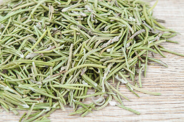 Dried rosemary spice on wooden background. Macro with shallow depth of field.