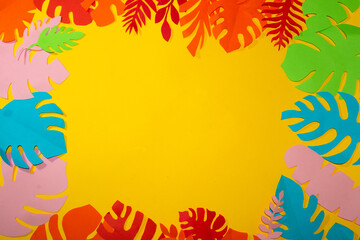 Fototapeta na wymiar yellow background for copy space surrounded by colorful jungle leaves, creative summer tropical design, flat lay