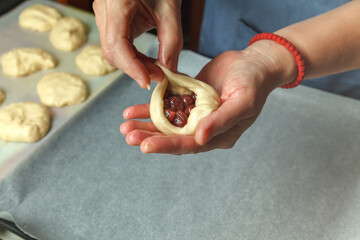 Pastry chef puts a spoonful of cherry in prepared bread dough