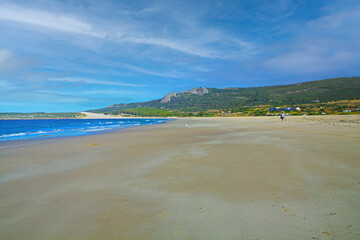 Quiet morning empty beach scene, low tide atlantic sea, green hills - Zahara de los Atunes, Costa de la Luz, Spain