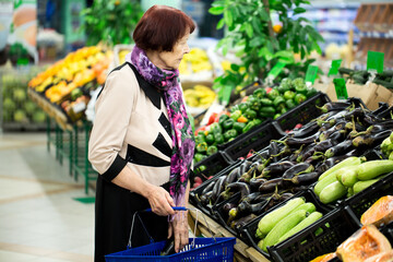 Grandma,old woman picks eggplant at the supermarket. close up. hands