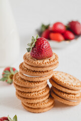 Breakfast with sweet sandwich cookies and fresh red strawberry on a white table.
