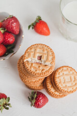 Breakfast with sweet sandwich cookies and fresh red strawberry on a white table. Top view.