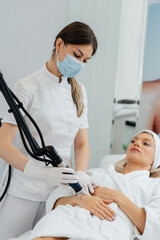 A young girl gets carbon peeling for the skin of her hands in a beauty salon. Laser pulses cleanse the skin. Hardware cosmetology. The process of photothermolysis, warming the skin.