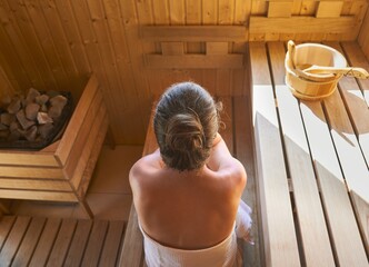 Top view image of woman relaxing in the wellness spa, sweating in Finnish sauna.