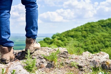 Man hiker standing on the top of the cliff edge, enjoying view.