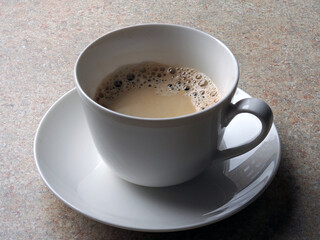 aromatic coffee in a white cup on the kitchen table