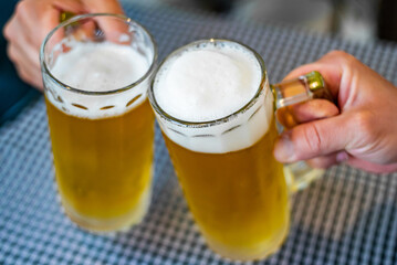 two glass of beer in man hand. Beer glasses clinking in bar or pub