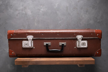 Vintage suitcase on wood shelf at wall. Old vintage suitcase
