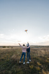 A happy couple flies a kite and spends time together outdoors in a nature reserve. Happy relationships and family vacations. Freedom and space.