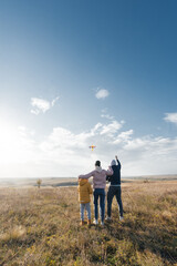 A happy family with children flies a kite and spends time together outdoors in a nature reserve. Happy childhood and family holidays. Freedom and space.