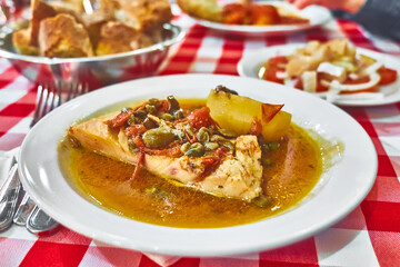 Stockfish (white/ without tomatoes) in Messina style. Cod stewed with cherry tomatoes, caper, olive oil and potato. Traditional plate of Messina, Sicily, Italy