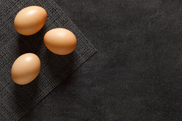 Eggs whole chicken, three pieces, on dark background, top view, space to copy text.