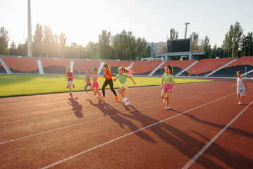 A large group of girls, got ready at the start before running at the stadium during sunset. A healthy lifestyle.