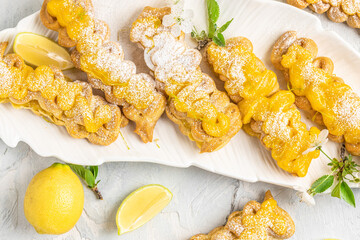 French dessert eclairs with lemon curd topping with fresh lemons on a light background, Restaurant menu, dieting, cookbook recipe top view