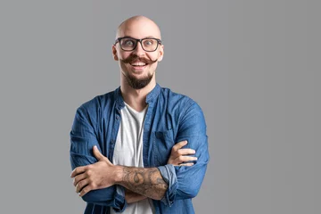 Fotobehang Studio shot of young happy man smiling with wide open eyes while wearing eyeglasses with arms crossed © zamuruev