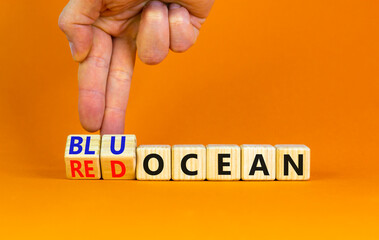 Blue or red ocean symbol. Businessman turns cubes, changes concept words Red ocean to Blue ocean. Beautiful orange table orange background. Business ecological blue or red ocean concept. Copy space.