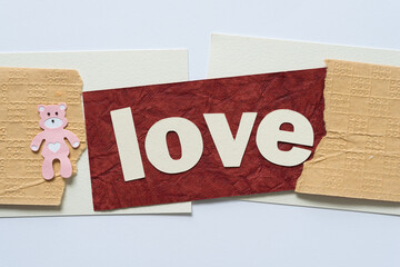 abstract paper background with the word love (and a pink paper bear with a heart)