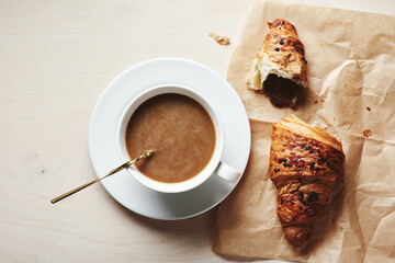 Cup of coffee with cream and chocolate croissant.