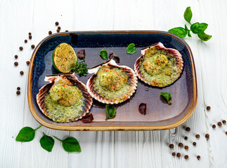 Scallops baked in a shell with cheese and pesto sauce