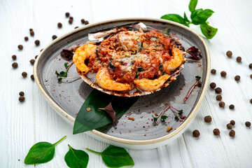 Shrimps baked in scallop shell with tomato sauce and vegetables