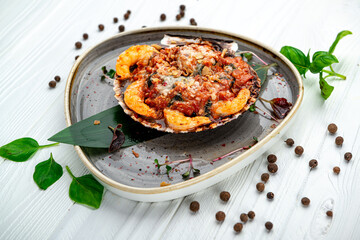 Shrimps baked in scallop shell with tomato sauce and vegetables