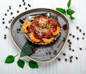 Shrimps baked in scallop shell with tomato sauce and vegetables