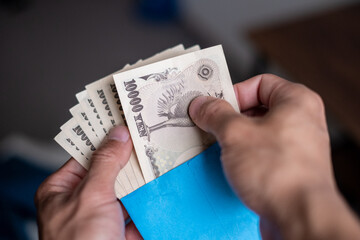Counting Japanese banknotes by hand from inside a salary envelope