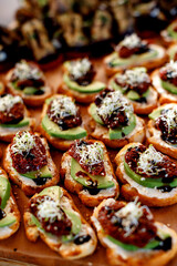 Sandwiches and tartlets with sun-dried tomatoes, avocado, cheese and balsamic vinegar. soft focus