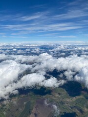 Beautiful cumulus clouds from the height of an airplane flight, in sunlight and with a streak of blue sky on the horizon. Travel concept.