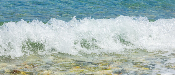 White waves on the beach. Sea coast on a sunny day. Summer vacation concept
