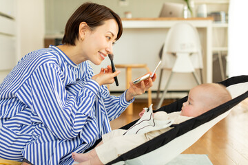 化粧をしながら赤ちゃんをあやす母親