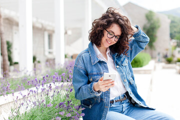 Happy girl using mobile phone on town street outdoor. Young woman