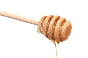 Wooden dipper with honey falling down isolated on a white background. Golden organic floral honey...