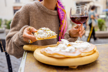 Woman holding pizza and a glass of wine at outdoor restaurant. Concept of Italian gastronomy and...