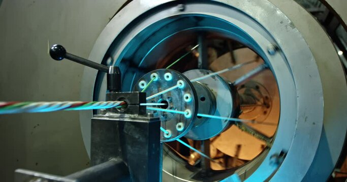 A rotating mechanism that coils several thin colored wires into one thick one. The work of the machine in the workshop for the production of electric cables for the needs of defense enterprises.