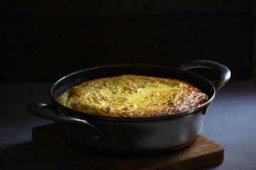 Rustic omelet with potatoes in a metal pan on the kitchen table.