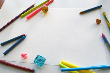 Color felt-tip pens and pencils, notepad and white sheet, top view. Creative artistic mockup with copyspace