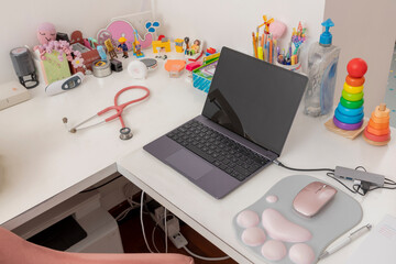 Laptop, stethoscope and pediatric equipment, on the desk of a pediatric office