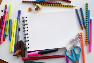 Color felt-tip pens and pencils, notepad and white sheet, top view. Creative artistic mockup with copyspace