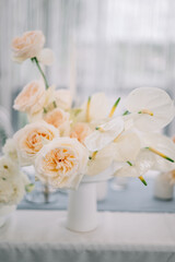 The composition of flowers on a festive table in the area of wedding party. Roses, callas 