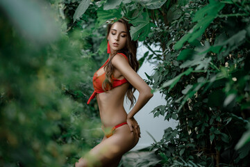 Portrait of a beautiful young girl in a bathing suit with clean and healthy skin. Model with green leaves near the body. beauty