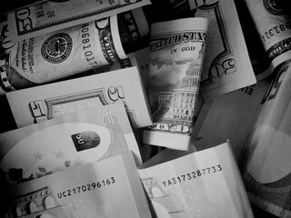 Cash banknotes dollars and euros are mixed up, a close-up shot. Black and white image.