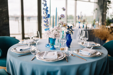 Festive wedding table. Stylish wedding table decoration and table setting in rustic style. Blue tablecloth. Vintage vase