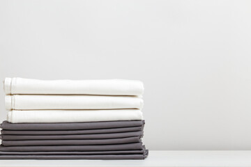 A stack of gray and white bed linens, sheets on the table.