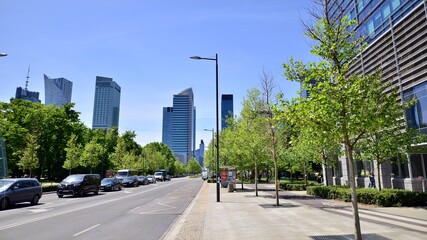 Obraz premium Glass skyscrapers against the blue sky and traffic in the city center. Colorful cityscape with buildings architecture and cars on the street. Sunny weather in the city.