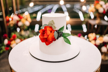 night wedding ceremony, the arch is decorated with flowers, candles and garlands of light bulbs and there is a wedding cake on the table