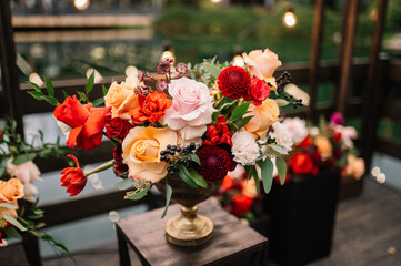 Beautiful flower composition with autumn orange and red flowers and berries. Autumn bouquet in vintage vase on a wooden table 