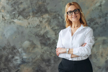 Middle age blond business woman wearing glasses standing over isolated textured background happy...