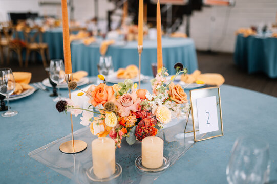 Cozy outdoor Wedding. Banquet. Chairs and honeymooners table decorated with candles, served with cutlery and crockery and covered with a blue tablecloth. 